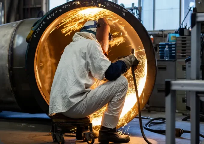 工場で水車部品を溶接する作業員